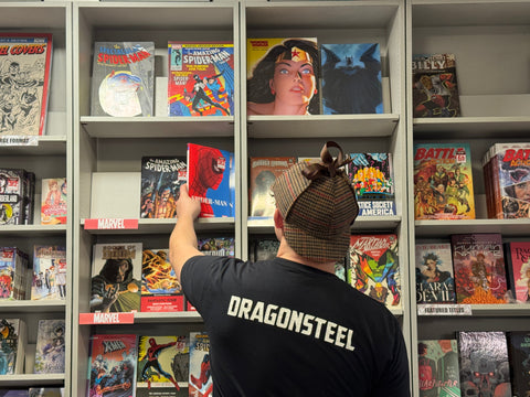 A Dragonsteel employee in a deerstalker cap reaches for a Spider-Man comic book on a shelf of other comics.